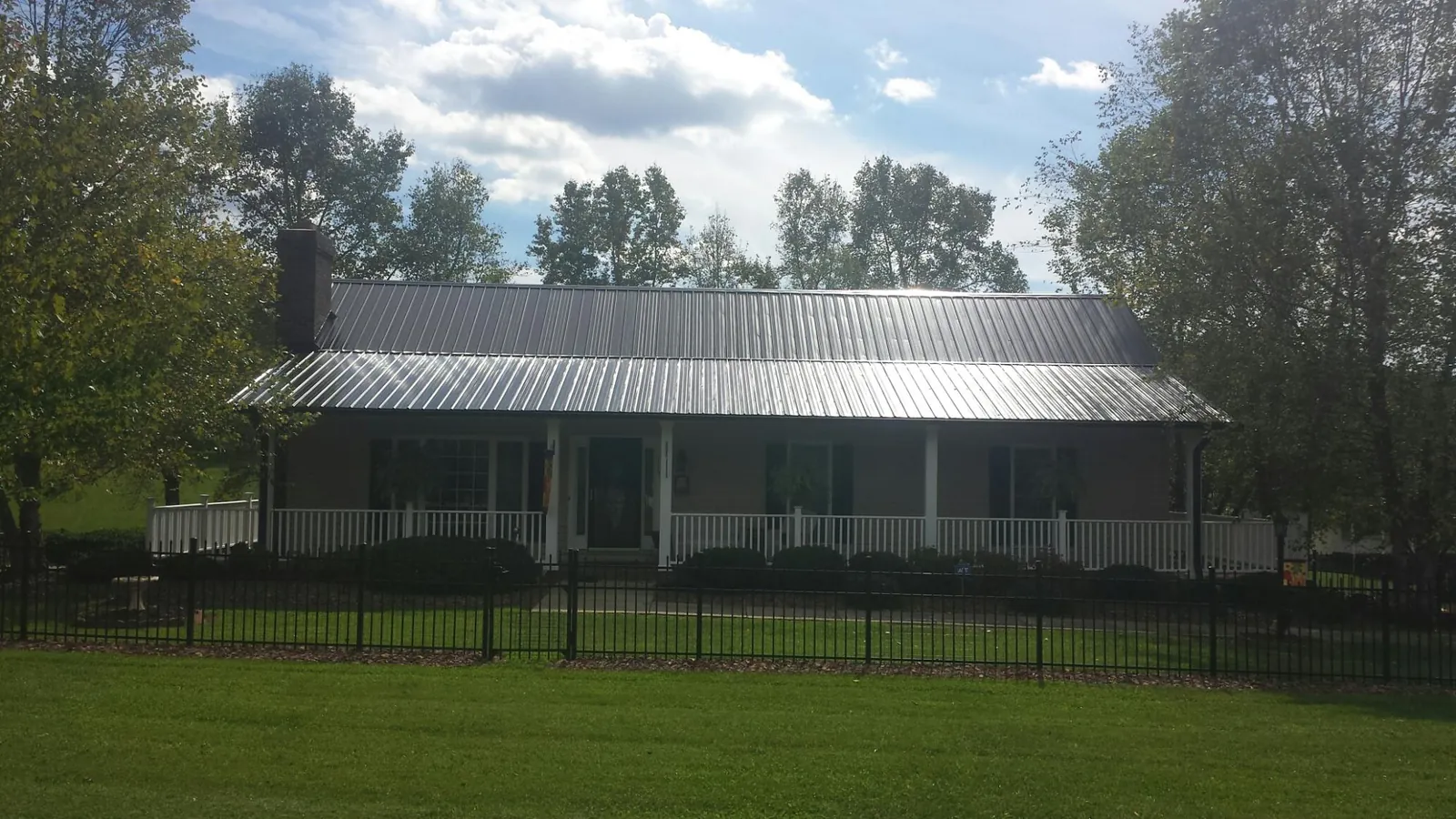 Gray metal roof on a brick ranch with a full width front porch — Gutter Guard Installation work by our crew in Uniontown