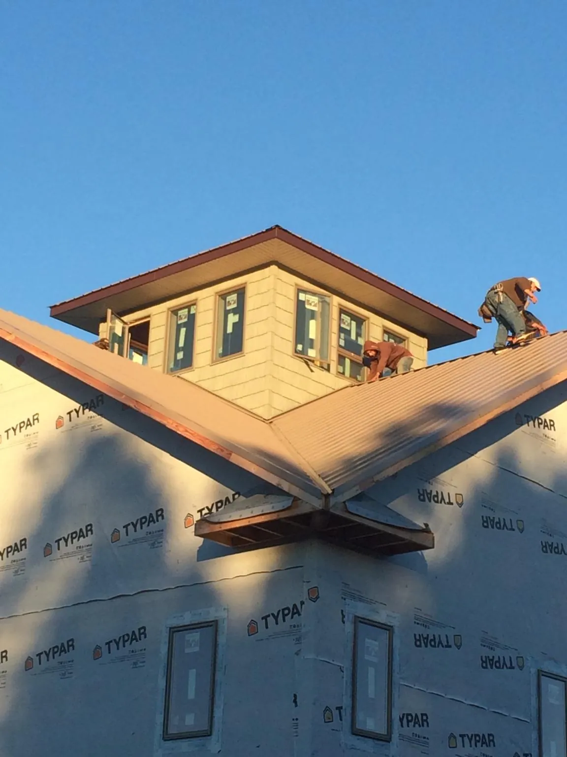Roofers working around a rooftop cupola on a new metal roof at sunset — Roof Waterproofing in Uniontown by Roofing Brothers